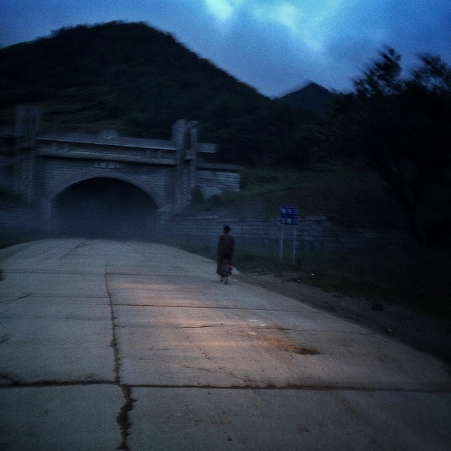 Севернокорейски мъж кара велосипед към входа на тунела Хамхън.