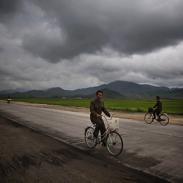 Севернокорейци карат велосипеди по националната магистрала в покрайнините на Пхенян.